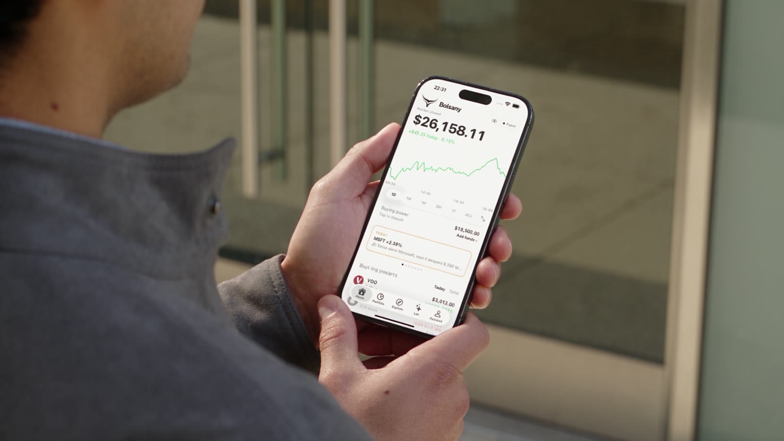 A person walks through the city, then looks at Bolsany on a phone.